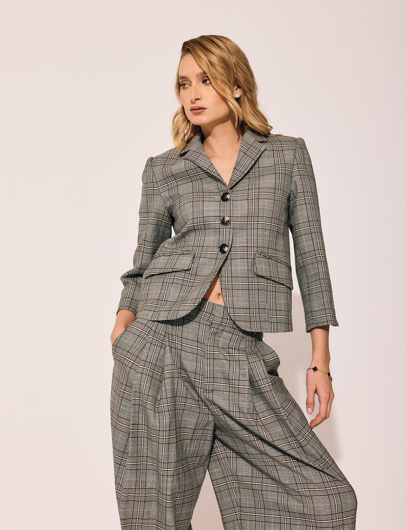 Woman wearing a gray plaid suit against a plain background